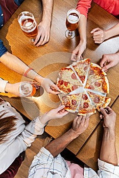 friends eating pizza with beer at restaurant