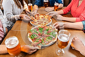 friends eating pizza with beer at restaurant