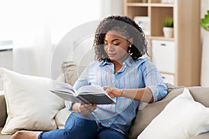 African american woman reading book at home photo
