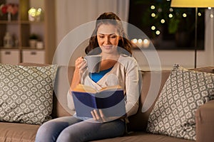 Young woman reading book at home in evening