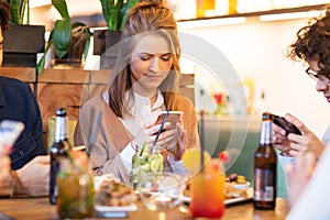 Friends with smartphones eating at restaurant