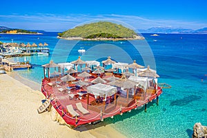 leisure platform under crystal clear waters with an islet in the background of the paradisiacal beach of Ksamil in Albania.