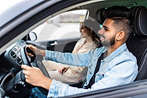 leisure, road trip, travel, family and people concept. Young happy indian man and woman driving in car