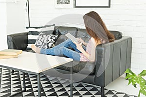 Leisure, technology and people concept - young brunette woman using tablet at home