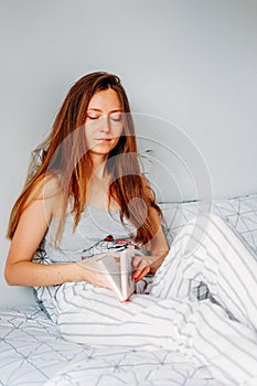 Leisure time activity. Young woman reading in bed
