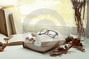Leisure time, reading and resting. window with autumn leaves, a book, glasses, time to read, autumn weekend concept