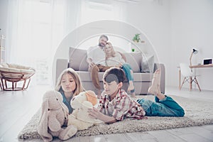 Leisure together. Happy family of four is enjoying at home, small kids are playing with toys, parents are on the sofa, hugging