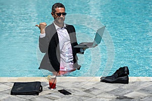 Leisure weekend and remote freelance work. Crazy comic business. Funny businessman in suit with laptop in swimming pool