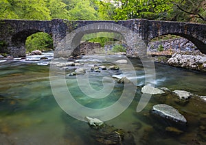 Leizaran river flows between the rocks under an old bridge in Andoain