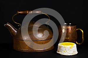 Lemon Cake with powdered sugar on dark background with copper tea pot and mug