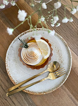 Lemon cheese tart with white ceramic plate on wooden table and chair in minimal coffee cafe.