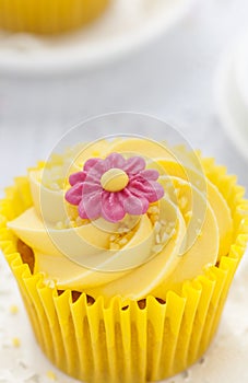 Lemon cupcake with butter cream swirl and fondant flower decoration