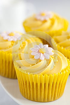 Lemon cupcakes with butter cream swirl and fondant flower decoration