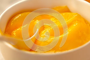 Lemon curd in a sausepan white bowl.Close-up yellow smooth background.Horizontal