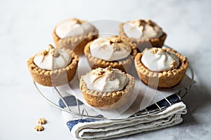 Lemon curd tartlets with whipped meringue on a wire rack on a gray background