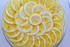 Lemon cut into slices on a white plate. Juicy round pieces of yellow lemon. Citrus is a source of vitamin and ascorbic acid