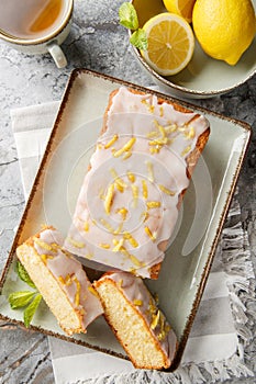 Lemon Drizzle Cake is a classic British cake known for its moist texture and vibrant lemon flavour closeup on the plate. Vertical