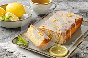 Lemon drizzle cake with lemon zest and icing is a classic British tea-time treat closeup on the plate. Horizontal