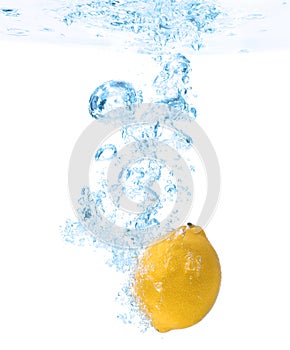 Lemon falling down into clear water against background