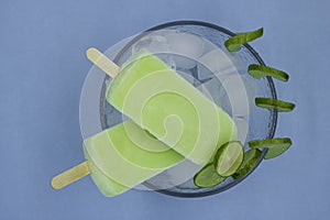 Lemon flavor ice pops, inside a deep plate with ice on a blue background, with lemon slices on the plate