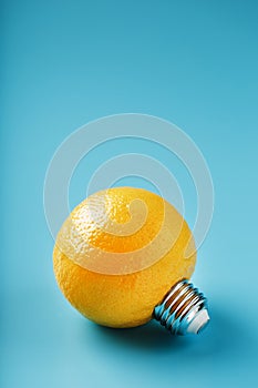 Lemon fruit as a light bulb on a blue background. The conceptual idea