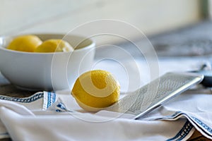 Three Lemons and Grater on White Cloth