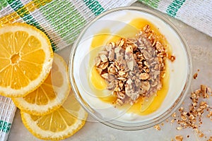 Lemon Greek yogurt with granola, overhead view on marble