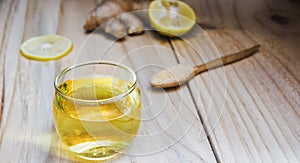 Lemon honey tea mixed with ginger in a clear glass with smoke, with a spoon and  brown sugar on a brown wood background, Healthy