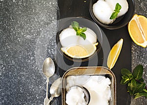 Lemon ice cream in black bowl.