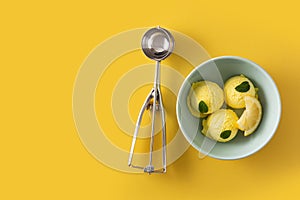 Lemon ice cream scoop decorated with mint leaves in bowl