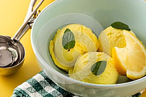 Lemon ice cream scoop decorated with mint leaves in bowl