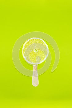 Lemon icecream with wood stick on light green background. Creative summe fruity popsicle sticks