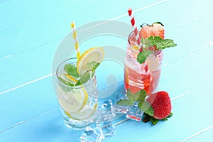 Lemon juice and strawberry juice mixing soda no alcohol in the glass garnish with mint leaves, sliced lime on blue wooden table