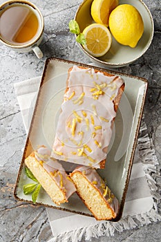 Lemon loaf cake, classic recipe, decorated with sugar icing closeup on the plate. Vertical top view