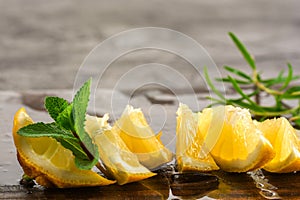 Lemon and mint leaves served on wooden kitchen board on concrete table, ingredient for summer cocktails and lemonade