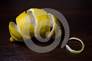 Lemon peel or lemon twist on a dark brown wooden background. Close up