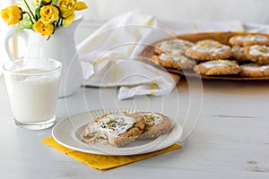 Lemon poppyseed keto cookies served with milk with a platter of more in behind.