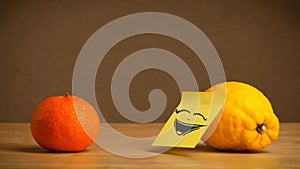 Lemon with post-it note laughing on orange