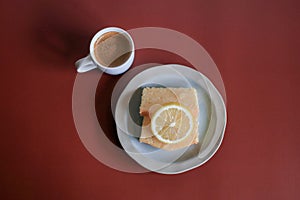 Lemon pound cake with white a cup of coffee on red background.