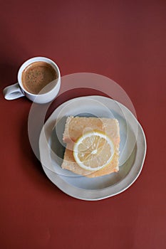 Lemon pound cake with white a cup of coffee on red background.