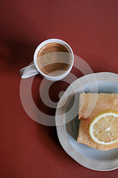 Lemon pound cake with white a cup of coffee on red background.