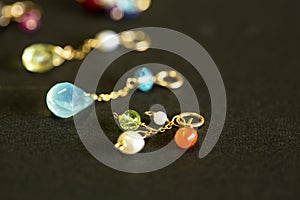 Lemon quartz, ruby, pearl,labradorite,apatite, green chalcedony, blue topaz necklace charm isolated on black background.