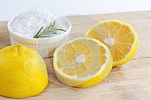 Lemon and sea salt - Beauty treatment with organic cosmetics with lemon ingredients on wood and rosemary background for body scrub