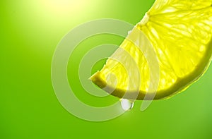 Lemon slice with drop of juice closeup. Fresh and juicy Lime over green background
