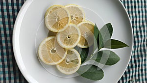 Lemon slices with leaves on a white plate