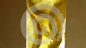 Lemon slices in sparkling water with bubbles, soda, lemonade in glass, rotation counterclockwise, turning.