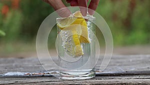 lemon in sparkling water in a glass on a table in the sun, water with lemon