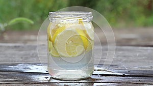lemon in sparkling water in a glass on a table in the sun, water with lemon