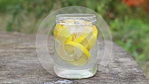 lemon in sparkling water in a glass on a table in the sun, water with lemon
