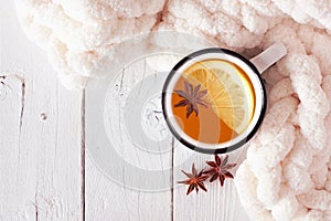 Lemon spice tea, top view on a white wood background with cozy blanket